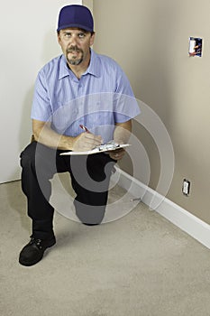 Service man kneeling with clipboard