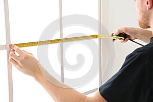 Service man measuring window for installation indoors photo