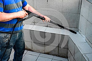 A service man is washing the swimming pool with a high-pressure washer. Swimming pool cleaning.