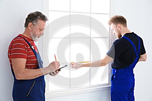 Service men measuring window for installation