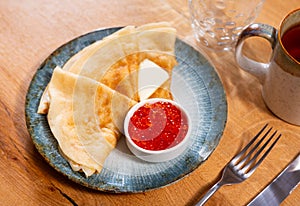 Service plate containing fried hotcakes with piece of butter and red caviar. Popular Russian dish photo