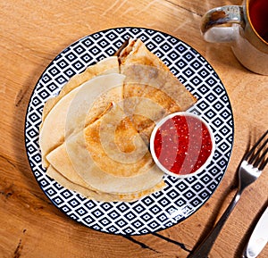 Service plate containing fried hotcakes with red caviar. Popular Russian dish