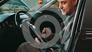 Service, repair, maintenance concept. Mechanic man sitting inside car with laptop making diagnostics at auto service