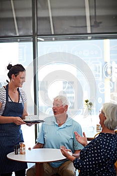 The service is speedy and friendly. a senior couple being served by a waitress.
