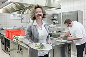 Service waitress in restaurant getting dish from pass in kitchen