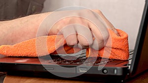 Service worker cleaning laptop keyboard buttons with microfibre cloth