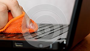 Service worker cleaning laptop keyboard buttons with microfibre cloth