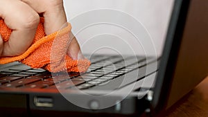 Service worker cleaning laptop keyboard buttons with microfibre cloth