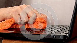 Service worker cleaning laptop keyboard buttons with microfibre cloth