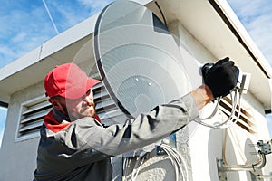 Service worker installing and fitting satellite antenna dish for cable TV