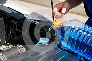 Service worker, pours in the tank washer fluid for washing car windows