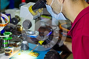 Service worker repairing mobile phone with microscope