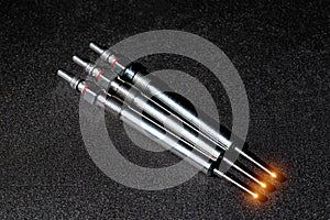Serviceable modern ceramic glow plugs on a gray background. Orange glow, heating element. Pre-heating of a diesel engine