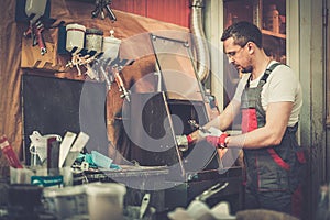 Serviceman in a car body workshop photo