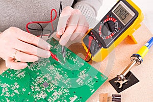 Serviceman checks PCB with a digital multimeter