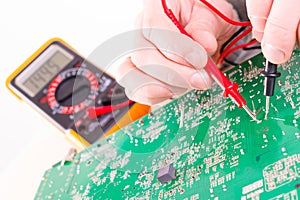 Serviceman checks PCB with a digital multimeter