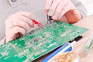 Serviceman checks PCB with a digital multimeter