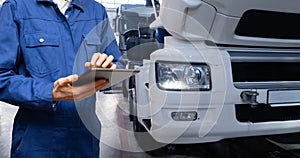 Serviceman with digital tablet on the background of the truck in the garage..