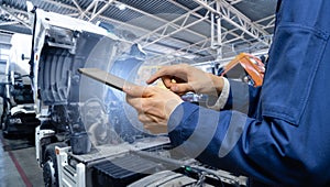 Serviceman with digital tablet on the background of the truck in the garage.