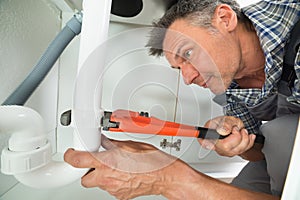 Serviceman Fixing Sink Pipe In Kitchen