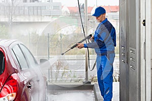 Serviceman With High Pressure Water Jet Washing Car