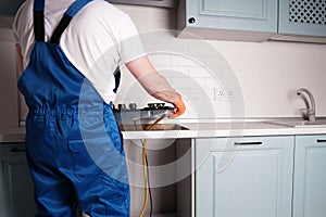 Serviceman installs  new gas hob