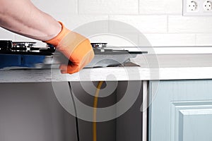 Serviceman installs  new gas hob in  kitchen countertop photo