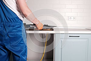 Serviceman installs  new gas hob in  kitchen countertop photo