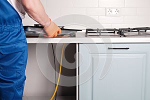 Serviceman installs  new gas hob in  kitchen countertop photo