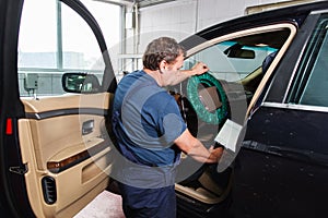 Serviceman making car diagnostics with laptop