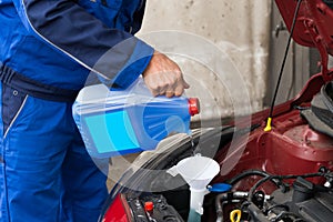 Serviceman Pouring Windshield Washer Fluid Into Car