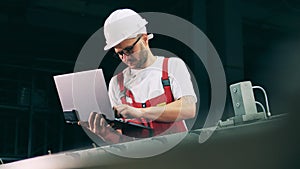 Serviceman is regulating a conveyor with his laptop