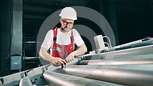 Serviceman is regulating a conveyor machine relocating metal