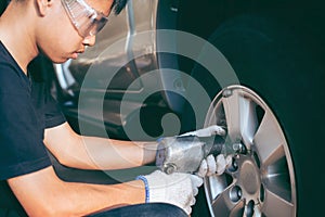 Serviceman removing bolt from a wheel using pneumatic gun, tire replacement