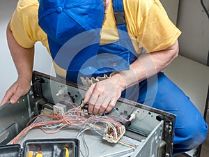 Serviceman replacing thermostat in the electric oven