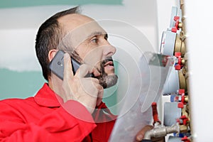 serviceman stood by water meters talking on smartphone