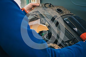 Serviceman stripping and opening up robotic lawnmower, motorized lawnmower being serviced on a table after a year of use in the