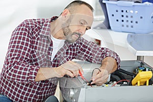 serviceman testing washing machine with multimeter