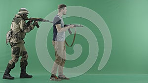 Serviceman in uniform with machine gun caughts civilian with a weapon against chromakey background