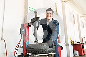 Serviceman In Uniform Using Tire Changer At Garage