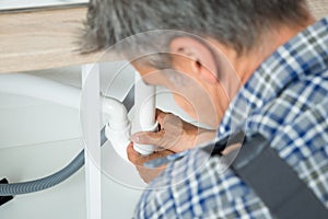 Serviceman Working On Pipes Under Kitchen Sink