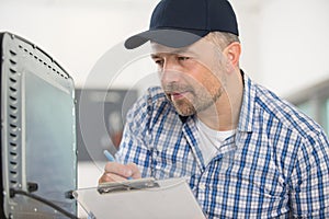 serviceman writing appliance serial number on paperwork