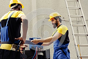 Servicemen repair air conditioner