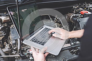 Services car engine machine concept, Automobile mechanic repairman checking a car engine with using computer diagnostics while photo