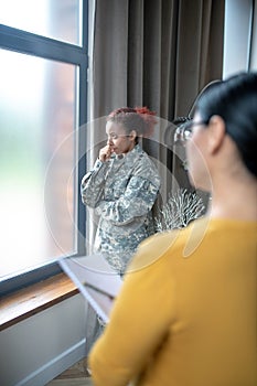 Servicewoman standing near window while visiting psychoanalyst photo