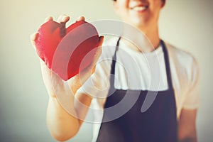 Servicing man in apron holding heart - customer relationship and service minded business concept