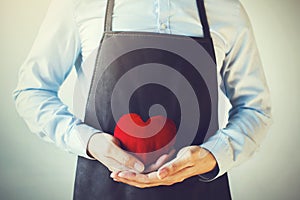 Servicing man in apron holding heart - customer relationship and service minded business concept