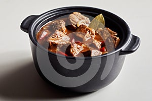 Serving of beef goulash in a cast iron pot photo