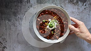 Serving a Bowl of Chili with Beans on a concrete background