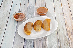 serving of Colombian corn empanadas stuffed with shredded chicken meat are sauces